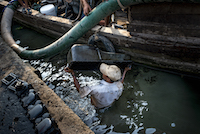 A worker cleans an oilpan in the river